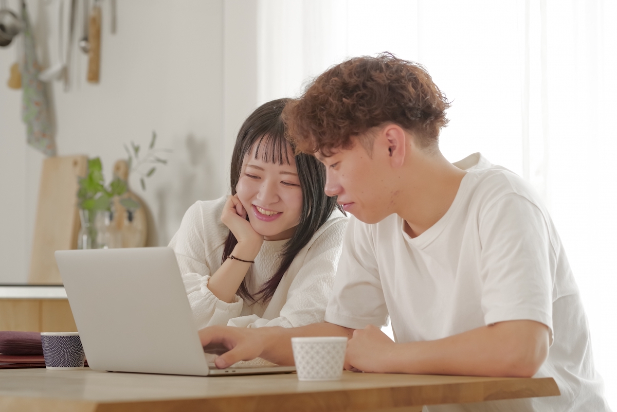 パソコンを見ながら相談する男女の写真