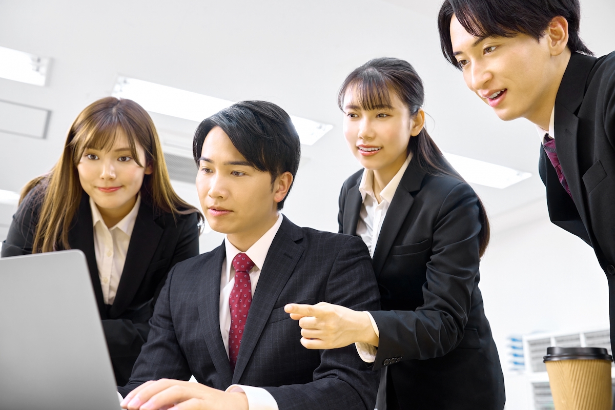 社内でパソコンを囲んで相談する様子の写真